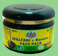 A jar of Multani + Banana Face Pack on a plain white background. The jar has a dark green lid, a gold band, and a yellow label with blue text and illustrations of a face mask and banana.
